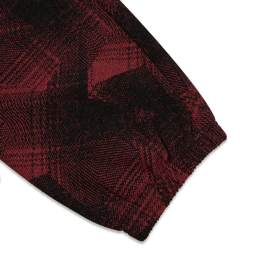 Close-up of a red and black patterned sleeve with an elastic cuff, echoing the bold style of Sp5der Sweatpants – Unisex Red and Black Patterned Cotton Sweatpants with Graphic Detail seen in streetwear jogger collections.
