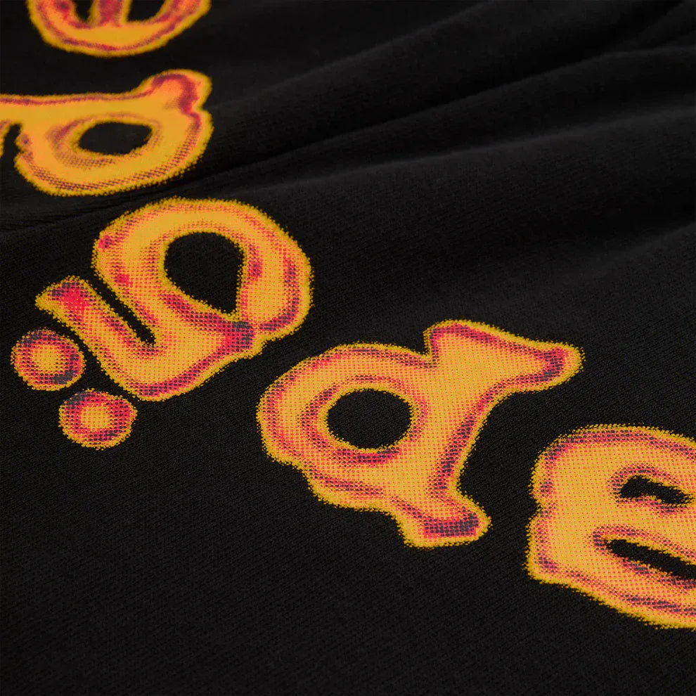 Close-up of bold yellow and orange outlined "de" text on black fabric, reflecting the iconic flame logo of Sp5der Sweatpants – Unisex Black Cotton Sweatpants with Flame Front Logo Print, in a classic streetwear jogger style.