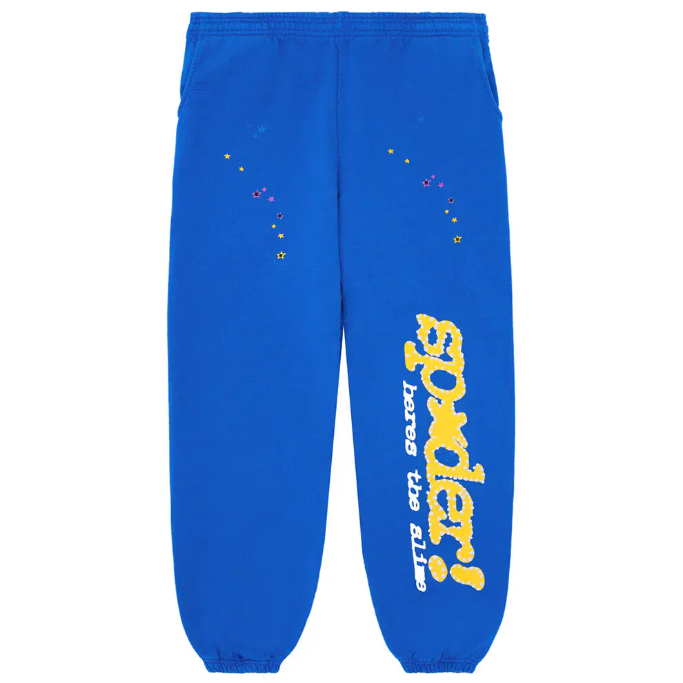 The Sp5der Sweatpants are unisex blue cotton joggers with an elastic waistband, yellow side logo, and star prints—streetwear style perfect for everyday comfort.