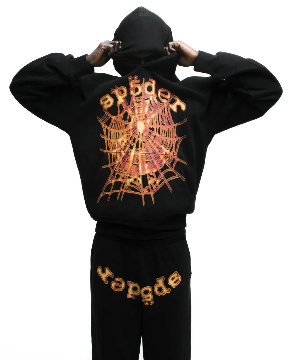 Person facing away in a Sp5der Web Graphic Hoodie – Black & Orange 440GSM Heavyweight Streetwear, with orange spider web graphics and "sp5der" on the back and pants, set against a white background.