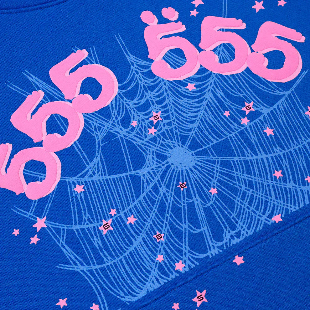 The Sp5der “555” Hoodie is a royal blue 440GSM heavyweight streetwear pullover featuring pink "555" text repeated above a white spider web and small pink stars, inspired by the iconic Sp5der hoodie design.