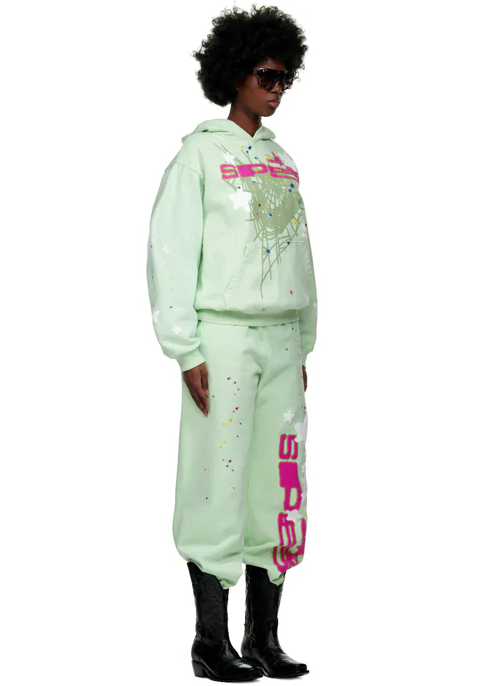 Person wearing a Sp5der “Mint Star Web” Hoodie in mint green, an oversized 440GSM heavyweight streetwear pullover, with sweatpants, black sunglasses, and boots, channeling Y2K streetwear vibes against a plain background.
