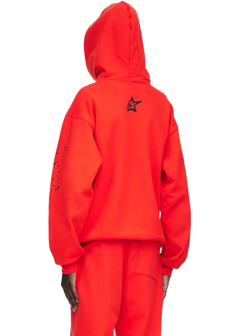 A person faces away, wearing the Red Graphic Hoodie with Spider Web Print and Star Details—a comfort-fit pullover featuring a black star graphic on the upper back and small black dots on one sleeve, paired with matching pants.