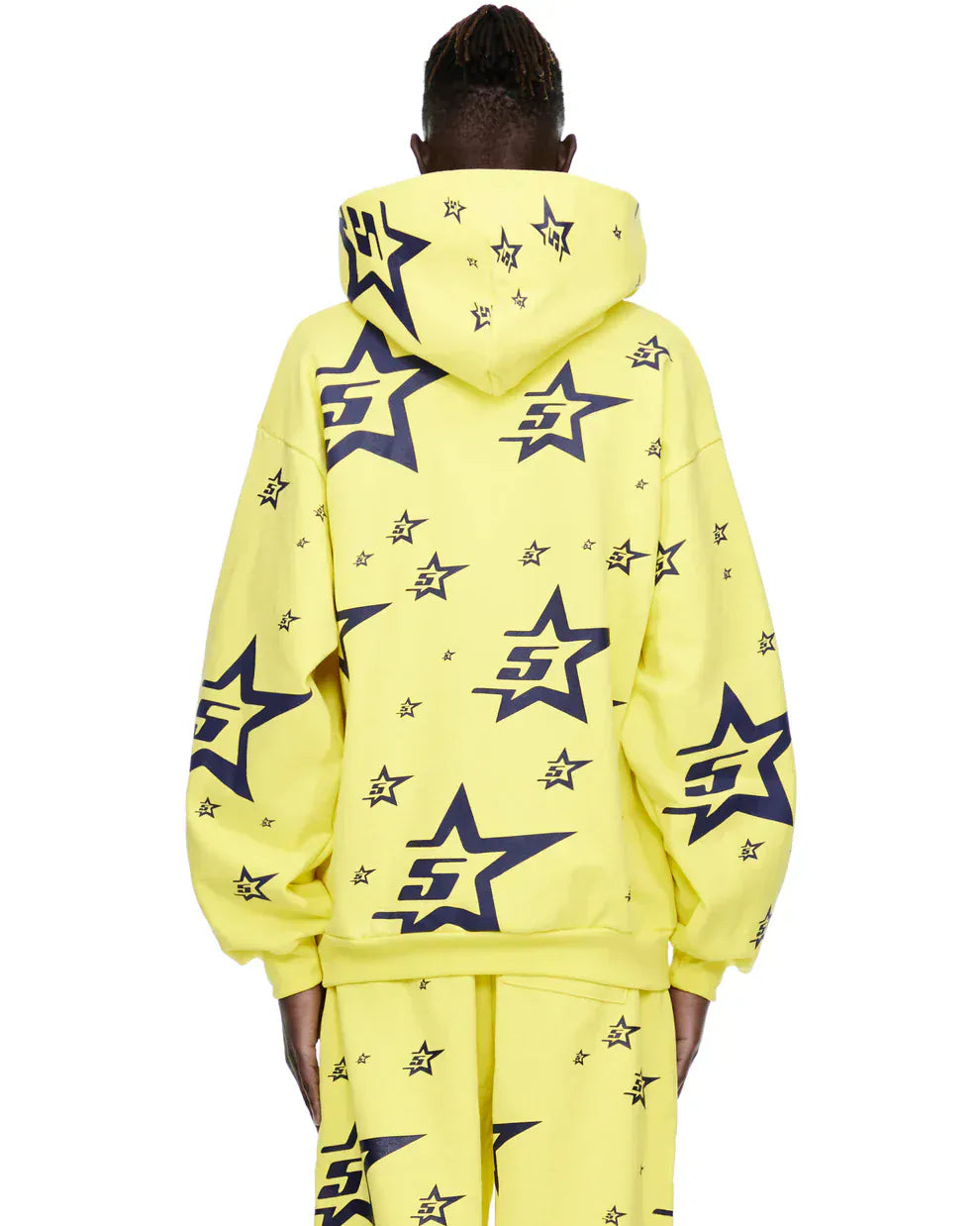 Person wearing the Yellow All-Over Star Graphic Hoodie – Comfort Fit Pullover Hoodie, styled with matching pants featuring black star and S logos, shown from behind against a plain background.